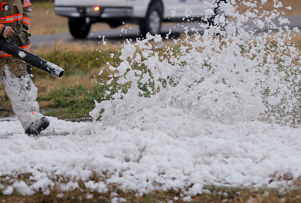 A firefighter from the Boone County Fire District blows foam away